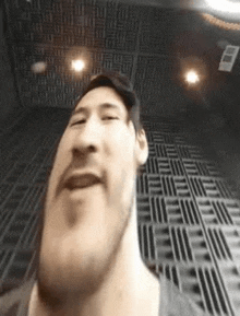 a man with a beard is taking a selfie in a room with a patterned ceiling .