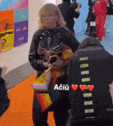 a woman is walking down an orange carpet with a rainbow purse and a sign that says united by music