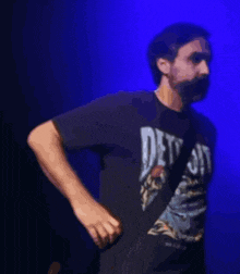 a man with a beard is wearing a black shirt with the word detroit on it