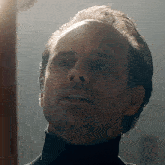 a man wearing a black turtleneck is looking up