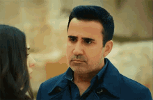 a man in a blue coat is looking at a woman in a black shirt