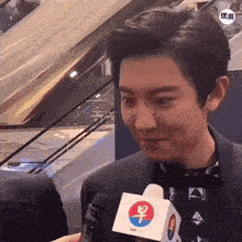a man in a suit is talking into a square microphone with a chinese symbol on it