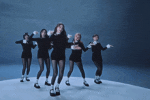 a group of women are dancing together in a blue room