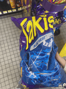 a person holding a bag of blue heat saki chips