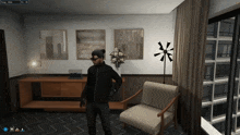 a man in a black jacket stands in a room with a chair