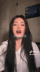 a woman with long black hair is making a funny face and has a tiktok sticker on her face