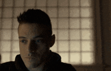 a close up of a man 's face in front of a window with squares