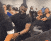 a man in a black shirt is dancing with a woman in a crowded room .