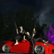 a couple of men sitting on top of a red sports car holding guns