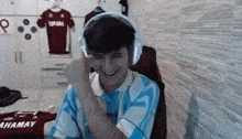 a young man wearing headphones and a blue shirt is sitting in a chair .