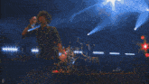 a blurry picture of a man playing a guitar on a stage with the letter d in the corner