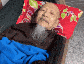 an older man with a beard is laying in a hammock with a blue blanket