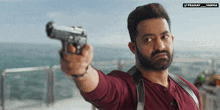 a man with a beard is pointing a gun at the camera with a watermark that says pranay varma
