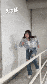 a woman in a plaid shirt and ripped jeans is running down a staircase