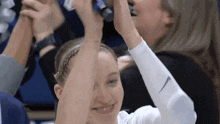 a woman wearing a white nike sleeve holds her hands up in the air