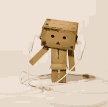 a cardboard box man wearing headphones with the amazon logo on it