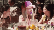 a woman wearing a pink baseball cap sits at a table with other women