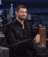 a man in a suit is sitting in a chair with his eyes closed and smiling .