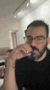 a man with glasses and a tattoo on his wrist is smoking a cigarette