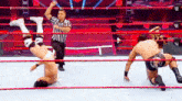 two men are wrestling in a wrestling ring with a referee standing behind them .