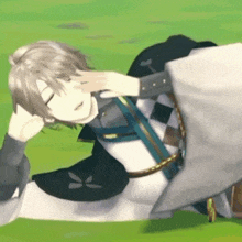 a man is laying on the grass with his hand on his face .