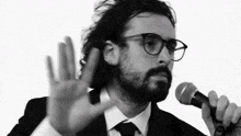 a man with glasses and a beard holds a microphone
