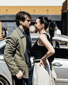 a man and a woman are standing next to a car