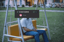 a man sits on a swing with a sign above his head that says timia