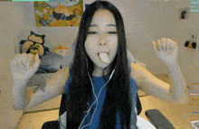 a woman wearing headphones sticks out her tongue in front of a stuffed animal that says snorlax