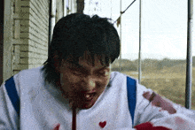 a man with blood on his face is holding a bloody object in his hand .
