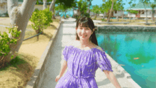 a woman in a purple off the shoulder dress is smiling