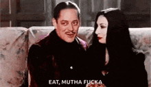 a man and a woman are sitting on a couch and the man is saying `` eat , mutha fuck . ''