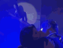 a man and woman are dancing in a dark room with blue lights .