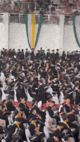 a large group of graduates are gathered in a gym