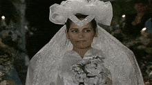 a woman in a white wedding dress holds a bouquet of white flowers