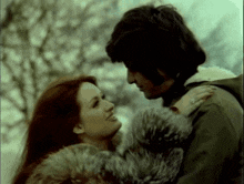 a man and a woman are looking into each other 's eyes and the woman is wearing a fur coat