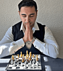 a man playing a game of chess with his hands folded in front of his face