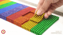 a person is playing with a bunch of different colored beads made by animatica