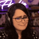 a woman wearing headphones and glasses is smiling and making a funny face .