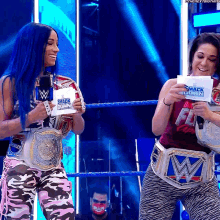 two women are standing in a wrestling ring holding a piece of paper that says smack down on it