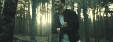 a man in a black jacket is running through the woods .