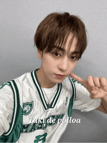 a young man wearing a green and white basketball jersey with the words taki de polloa written on the bottom