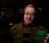 a man wearing headphones is drinking a green liquid from a glass .