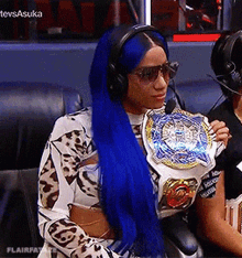 a woman with blue hair is holding a championship belt