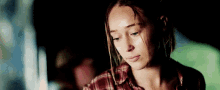 a woman in a plaid shirt is sitting in a car at night looking down .