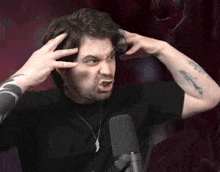 a man is making a funny face in front of a microphone while holding his head .