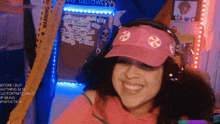 a woman wearing a pink hat and headphones smiles in front of a warning tape