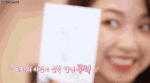 a woman is holding a card with a heart drawn on it and smiling .