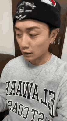 a man wearing a grey hawaii sweatshirt and a black beanie
