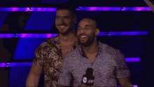 two men are standing next to each other and smiling in front of a microphone with the word aew on it